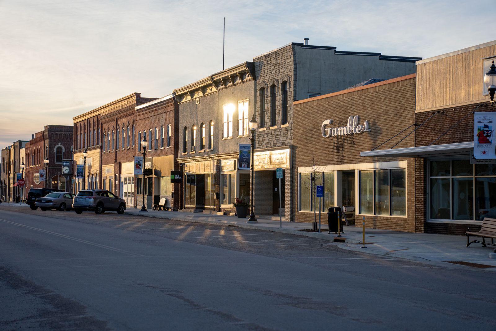 A small-town main street of brick storefronts in golden-hour light