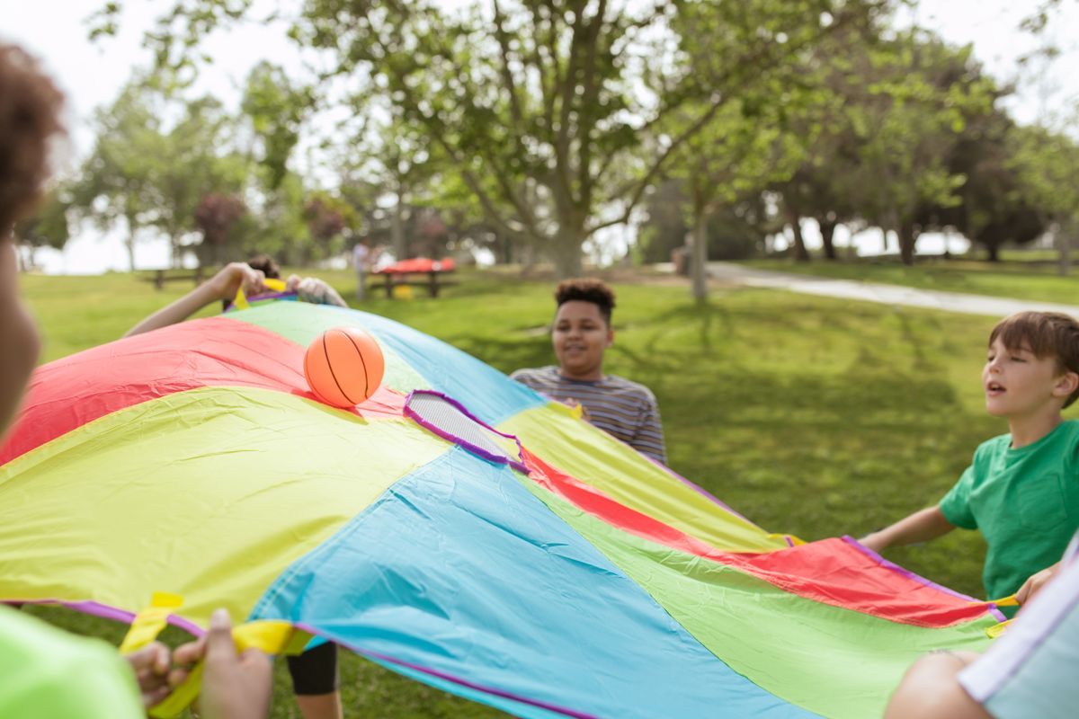 Kids playing a parachute game outdoors in a park