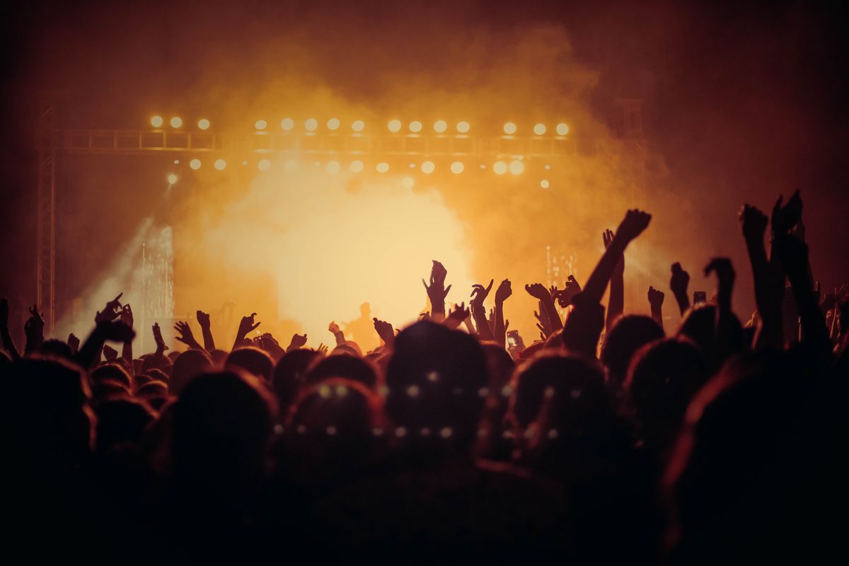 A concert crowd silhouetted against warm stage lights